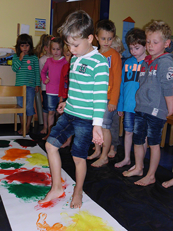 Die Kinder machen bunte Fußabdrücke auf eine Leinwand